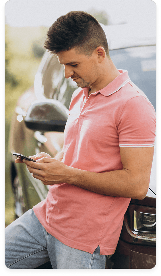 Homem usando smartphone próximo a um carro